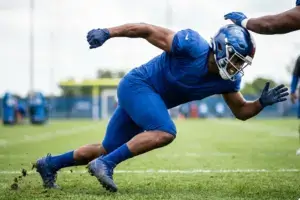 NFL edge rusher in Giants uniform executing pass rush technique during practice
