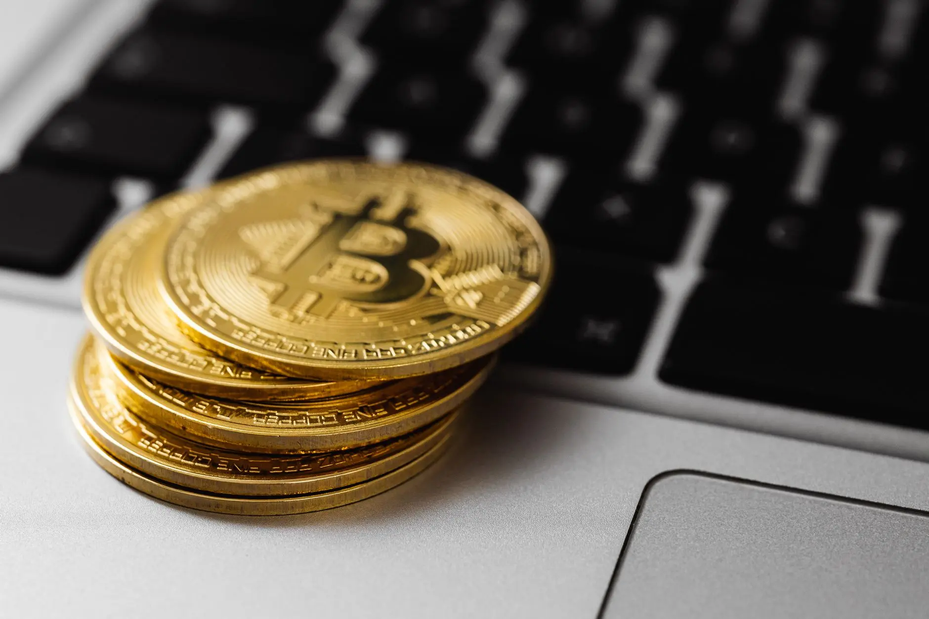Stacks of gold Bitcoin coins on a laptop keyboard.