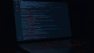 Dark laptop displaying data breach warning symbols and leaked information in moody lighting