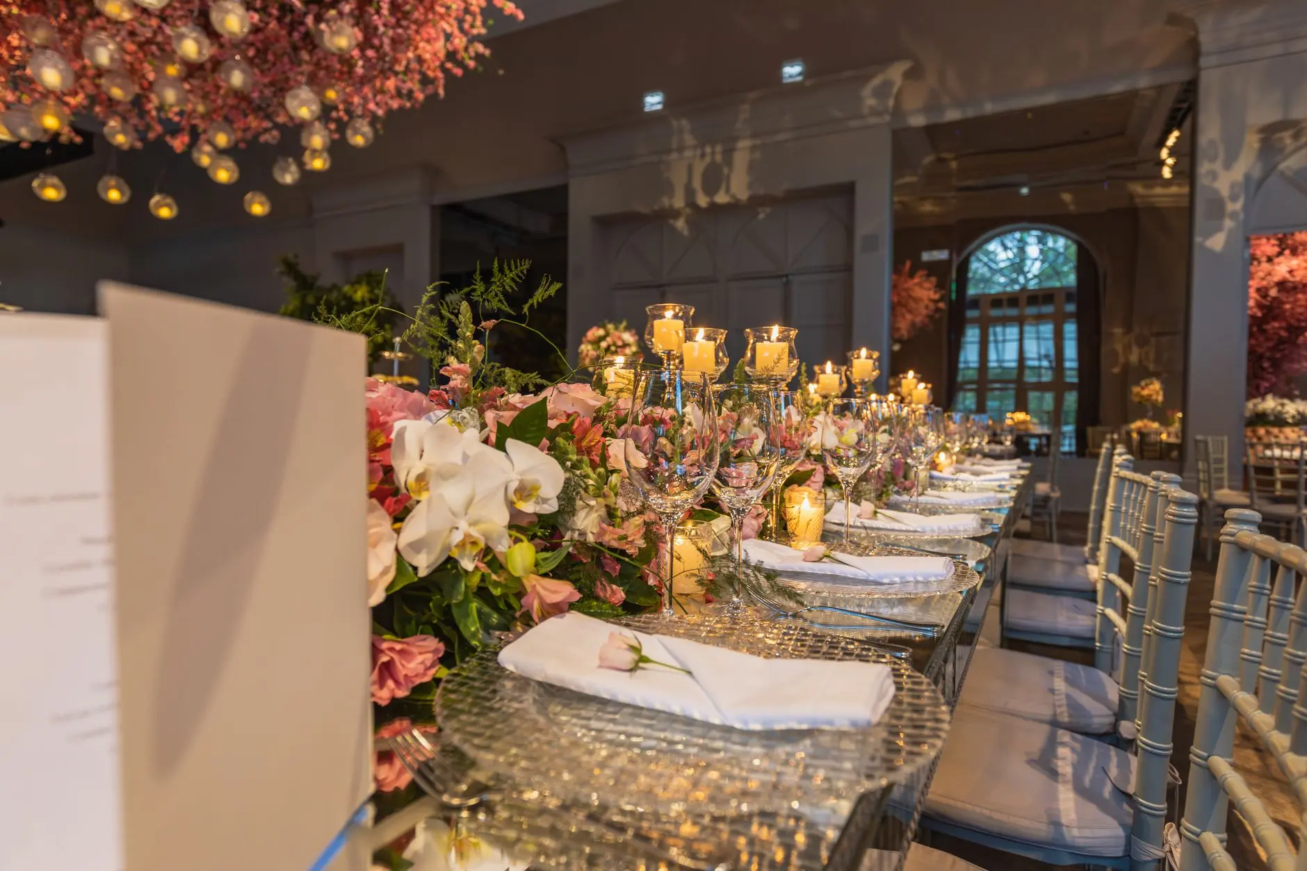 Elegant wedding reception table with floral centerpieces and candlelight.