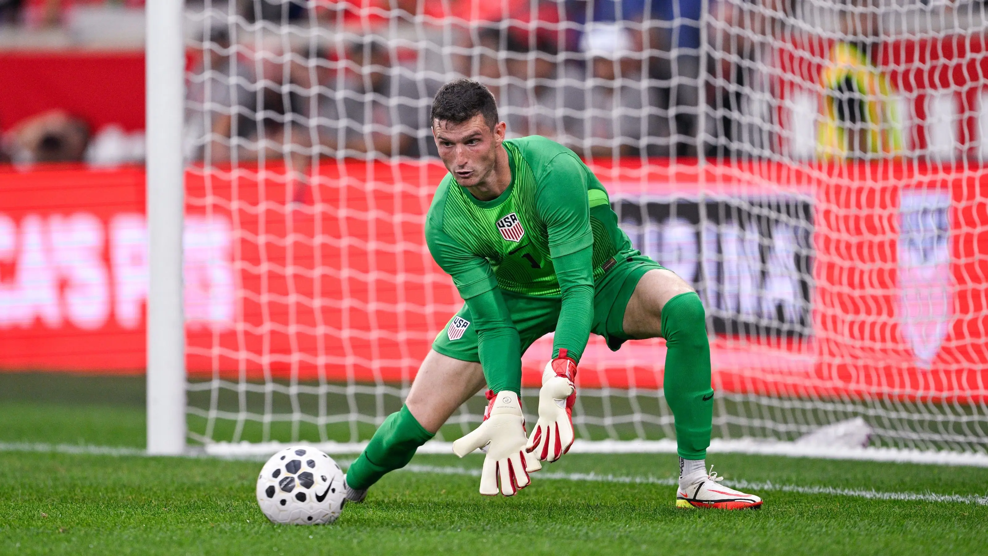 Matt Freese in green goalkeeper kit making a save during a soccer match.