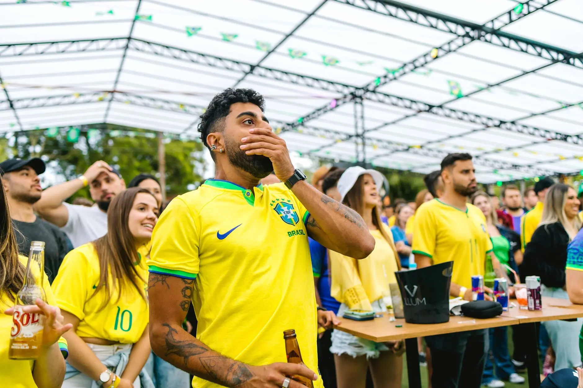 Fans in Brazil jerseys watching a soccer match in a lively outdoor venue.