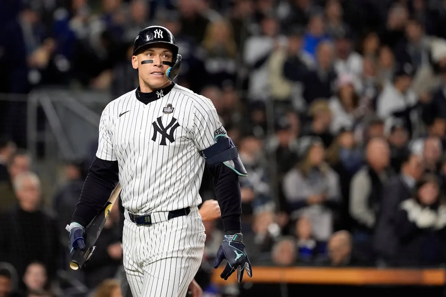 Aaron Judge in a Yankees jersey, standing at bat in a stadium with fans in background.