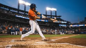 Mets player swinging bat at home plate during night game at Citi Field