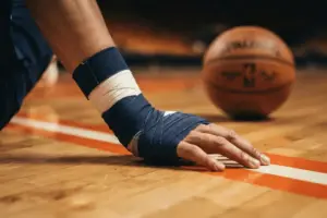 Basketball player's wrapped wrist on court symbolizing Jalen Brunson's recovery from surgery