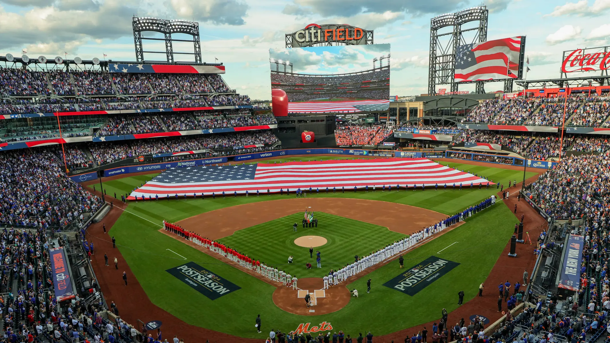 Citi Field stadium filled with fans during a postseason game with an American flag.