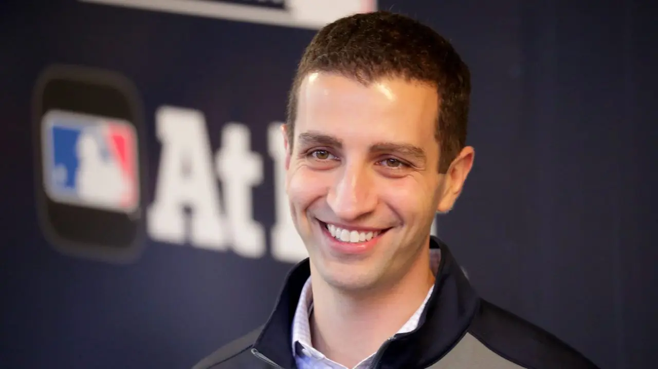 Close-up of David Stearns smiling, wearing a jacket, against a blue background.