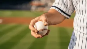 Baseball gripped in pitcher's hand wearing New York Yankees pinstripe uniform at stadium