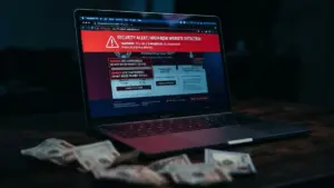 Laptop displaying fake FIFA World Cup ticket scam website with security warnings and cash on desk