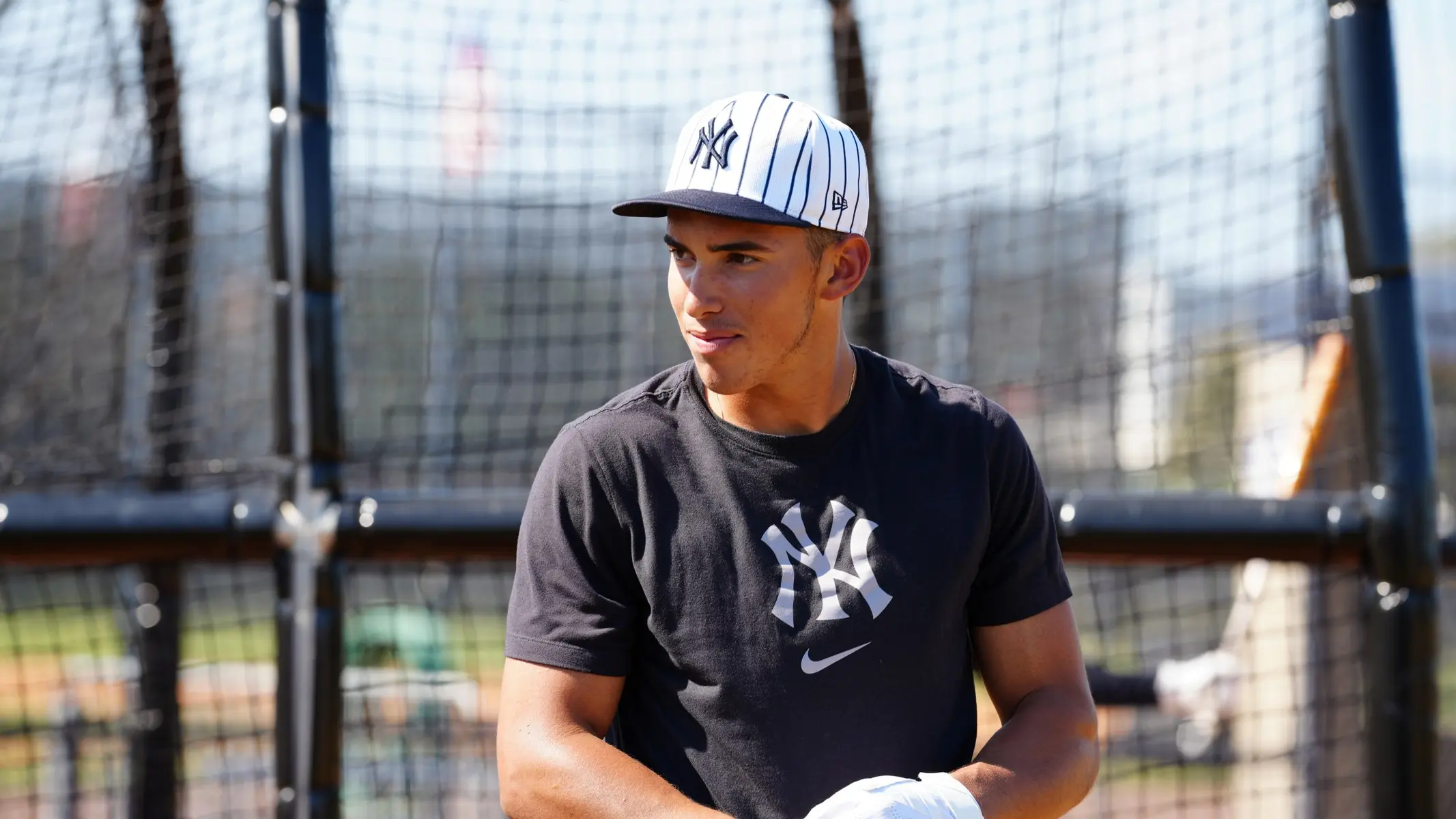 Young baseball player in a Yankees cap and shirt during practice.