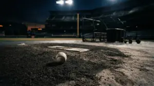 Empty baseball bullpen at night with lone baseball on mound after devastating loss
