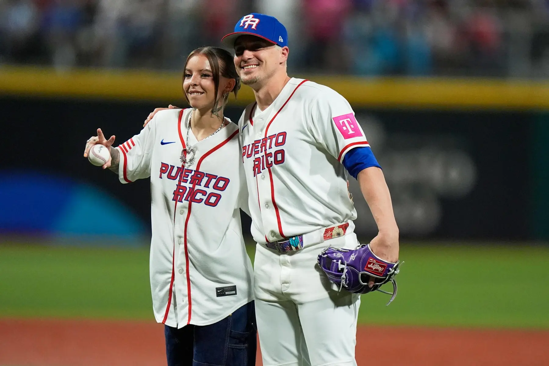 Two individuals posing in Puerto Rico baseball jerseys on a field.